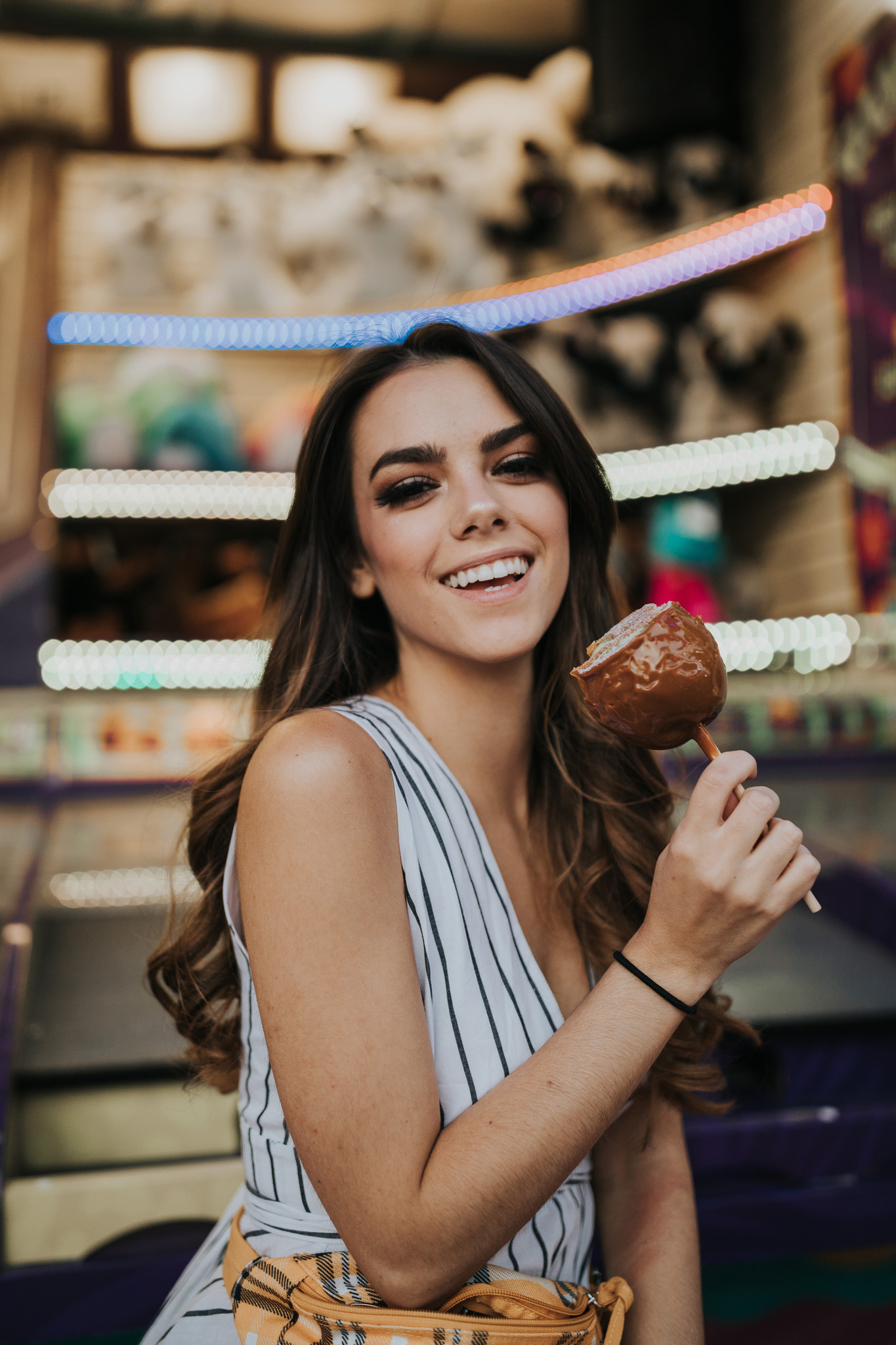 woman laughing holding candy apple at stampede midway game